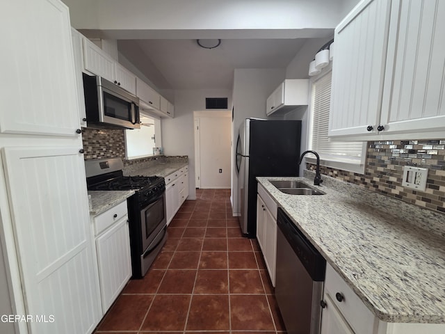 5121 Juliandra Ave, El Paso, TX 79924 - kitchen with stainless steel appliances, a sink, decorative backsplash, and white cabinets