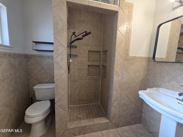 5121 Juliandra Ave, El Paso, TX 79924 - bathroom with tile walls, a shower stall, toilet, a wainscoted wall, and a sink