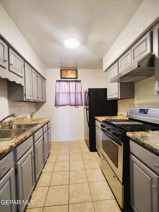 10077 Kirwood St, El Paso, TX 79924 - kitchen with stainless steel gas stove, a sink, gray cabinets, under cabinet range hood, and tile walls