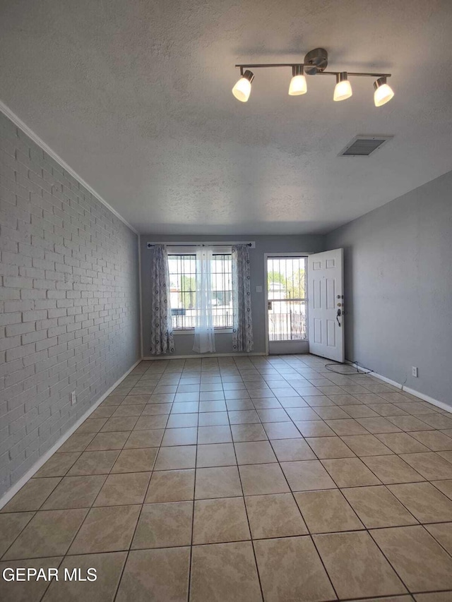 10077 Kirwood St, El Paso, TX 79924 - spare room with brick wall, a textured ceiling, light tile patterned flooring, baseboards, and ornamental molding