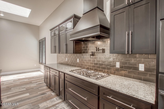 7363 Cimarron Rim Dr, El Paso, TX 79911 - kitchen featuring premium range hood, stainless steel gas cooktop, a skylight, and light stone countertops