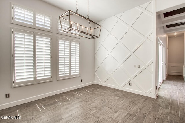 7363 Cimarron Rim Dr, El Paso, TX 79911 - unfurnished dining area with a chandelier, a decorative wall, wood finished floors, and baseboards