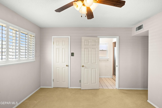 8213 Mineola Dr, El Paso, TX 79925 - unfurnished bedroom with carpet flooring, multiple windows, baseboards, ensuite bath, and a textured ceiling