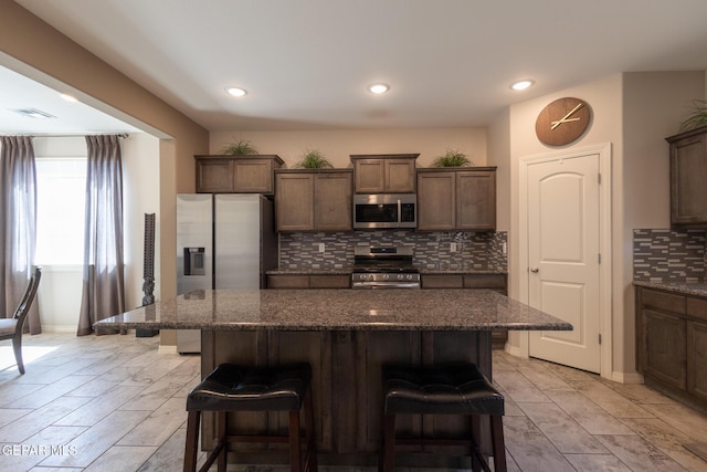 12301 Desert Heights Ct, El Paso, TX 79938 - kitchen featuring stainless steel appliances, a kitchen breakfast bar, backsplash, a kitchen island, and dark stone countertops