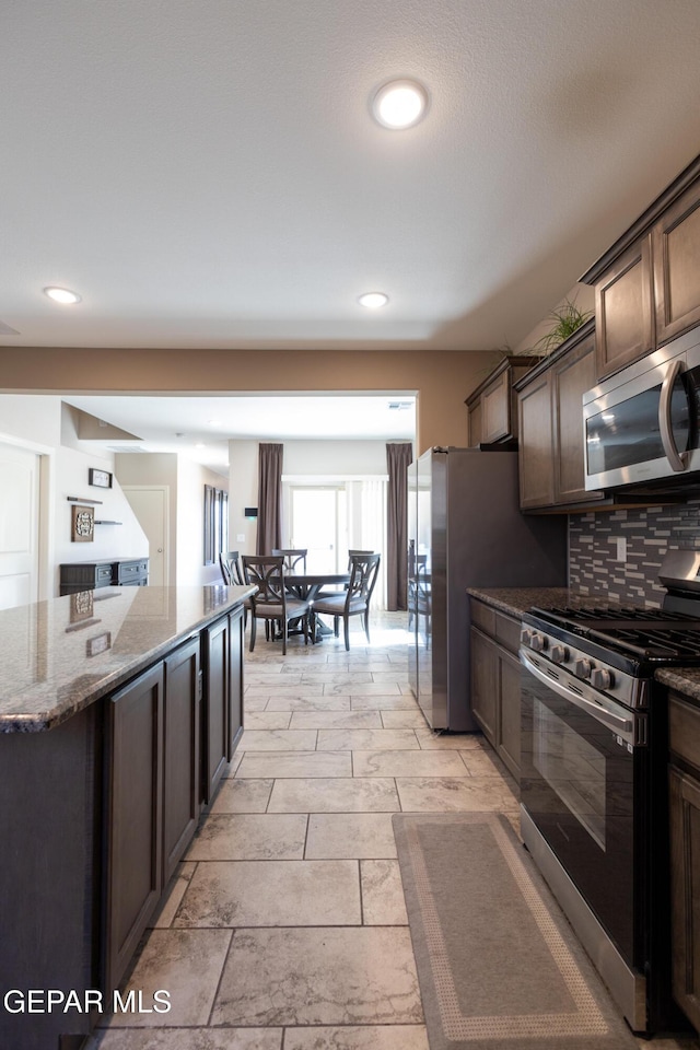 12301 Desert Heights Ct, El Paso, TX 79938 - kitchen with appliances with stainless steel finishes, dark stone counters, dark brown cabinets, tasteful backsplash, and recessed lighting