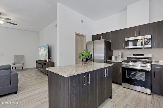 533 Cedarwood Ave, El Paso, TX 79928 - kitchen with appliances with stainless steel finishes, a ceiling fan, a kitchen island, decorative backsplash, and open floor plan