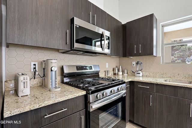 533 Cedarwood Ave, El Paso, TX 79928 - kitchen featuring stainless steel appliances, decorative backsplash, dark brown cabinetry, and light stone counters