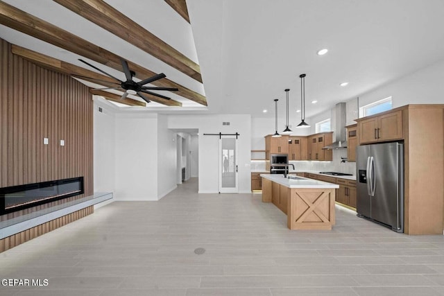 13399 Jeff Winton Dr, El Paso, TX 79928 - kitchen with appliances with stainless steel finishes, a barn door, open floor plan, light countertops, and wall chimney exhaust hood