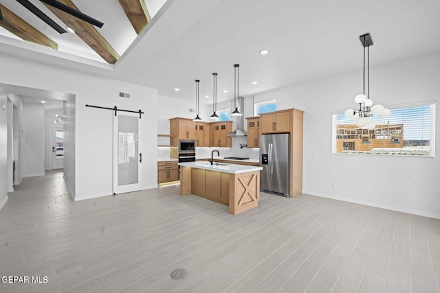 13399 Jeff Winton Dr, El Paso, TX 79928 - kitchen with appliances with stainless steel finishes, a barn door, a sink, wall chimney range hood, and light countertops