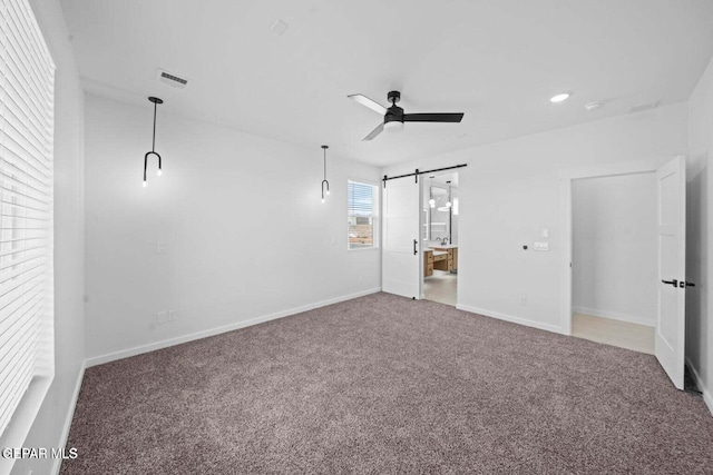 13399 Jeff Winton Dr, El Paso, TX 79928 - unfurnished bedroom featuring a barn door, carpet, baseboards, ensuite bath, and a ceiling fan