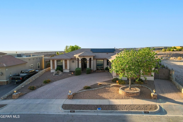 7301 Brays Landing Dr, El Paso, TX 79911 - view of front of house featuring curved driveway, solar panels, stucco siding, a gate, and a shingled roof