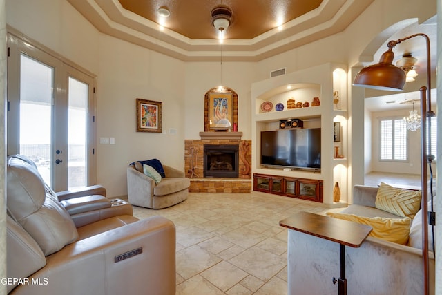 7301 Brays Landing Dr, El Paso, TX 79911 - living area with built in shelves, a chandelier, a raised ceiling, a high ceiling, and a stone fireplace