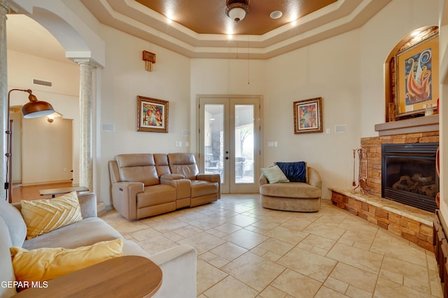 7301 Brays Landing Dr, El Paso, TX 79911 - living room featuring decorative columns, a raised ceiling, a high ceiling, arched walkways, and a stone fireplace