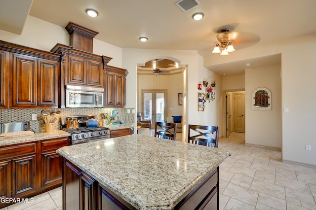 7301 Brays Landing Dr, El Paso, TX 79911 - kitchen with stainless steel appliances, a ceiling fan, arched walkways, and backsplash