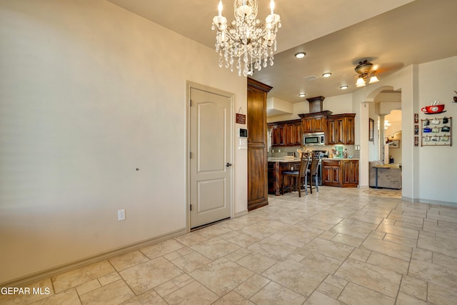 7301 Brays Landing Dr, El Paso, TX 79911 - kitchen featuring stainless steel appliances, a kitchen bar, baseboards, light countertops, and arched walkways