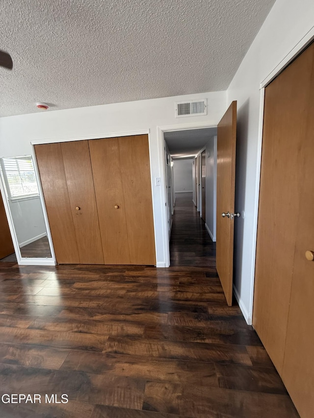 6220 Bel Mar Ave, El Paso, TX 79912 - unfurnished bedroom with dark wood-style flooring, a textured ceiling, baseboards, and a closet