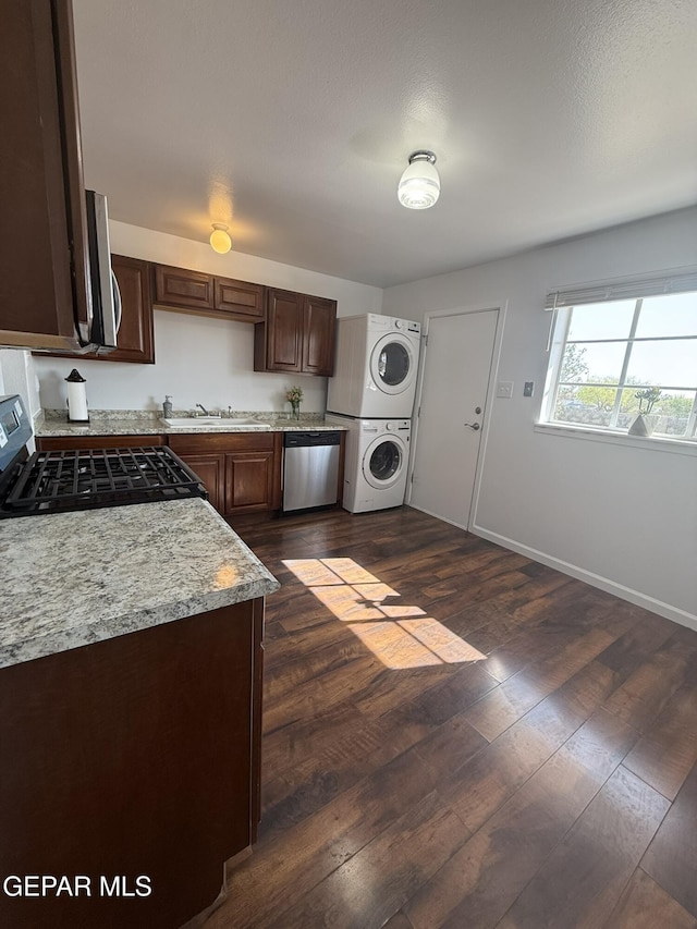 6220 Bel Mar Ave, El Paso, TX 79912 - kitchen featuring estacked washer and dryer, appliances with stainless steel finishes, light countertops, dark wood-style floors, and a sink