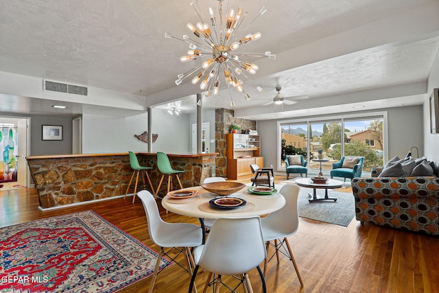 4012 Hastings Dr, El Paso, TX 79903 - dining room featuring wood finished floors, a chandelier, a textured ceiling, a ceiling fan, and a dry bar