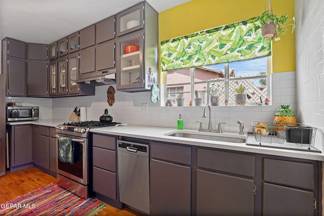 4012 Hastings Dr, El Paso, TX 79903 - kitchen with appliances with stainless steel finishes, a sink, under cabinet range hood, tasteful backsplash, and light countertops