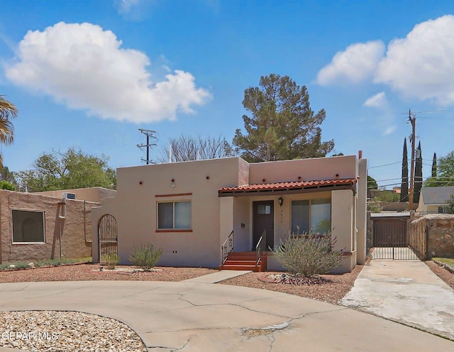 3408 Stanton St 233179, El Paso, TX 79902 - adobe home featuring a gate, stucco siding, a tiled roof, concrete driveway, and covered porch