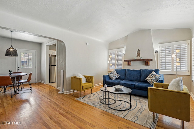 3408 Stanton St 233179, El Paso, TX 79902 - living room featuring light wood-style floors, arched walkways, lofted ceiling, a textured ceiling, and baseboards