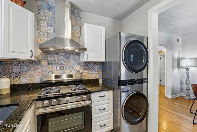 3408 Stanton St 233179, El Paso, TX 79902 - kitchen featuring gas stove, stacked washing machine and dryer, wall chimney range hood, light wood finished floors, and tasteful backsplash
