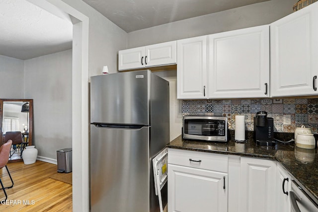 3408 Stanton St 233179, El Paso, TX 79902 - kitchen featuring appliances with stainless steel finishes, backsplash, light wood-type flooring, white cabinetry, and baseboards