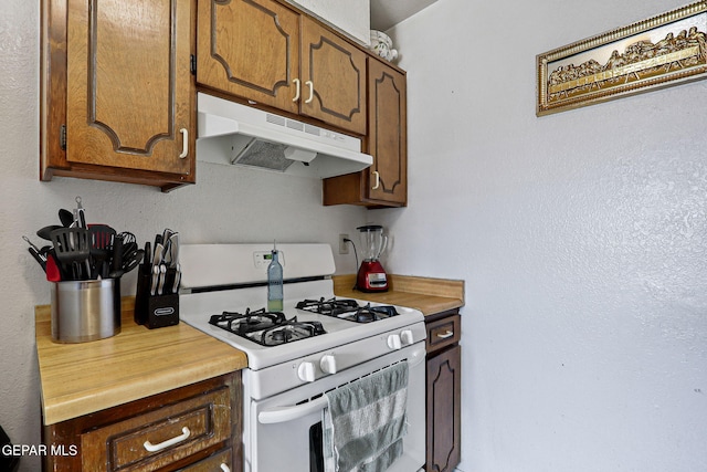 8957 Robert Dr Unit A & B, El Paso, TX 79904 - kitchen with white range with gas stovetop, under cabinet range hood, light countertops, and brown cabinets