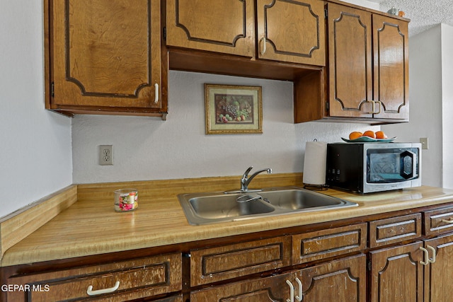 8957 Robert Dr Unit A & B, El Paso, TX 79904 - kitchen with stainless steel microwave, a sink, and a textured ceiling