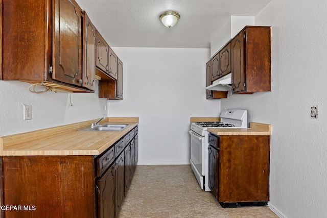 8957 Robert Dr Unit A & B, El Paso, TX 79904 - kitchen featuring white gas range oven, under cabinet range hood, a sink, baseboards, and light countertops