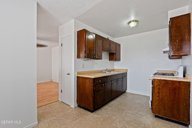8957 Robert Dr Unit A & B, El Paso, TX 79904 - kitchen featuring gas stove, light flooring, dark brown cabinets, light countertops, and baseboards