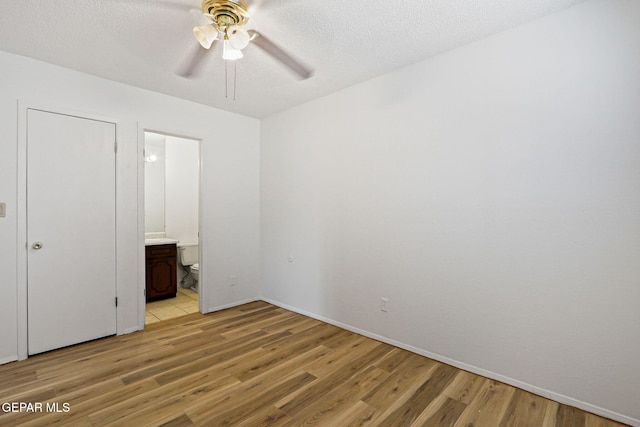 8957 Robert Dr Unit A & B, El Paso, TX 79904 - unfurnished bedroom featuring light wood-style flooring, ensuite bathroom, baseboards, a textured ceiling, and a ceiling fan