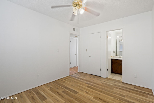 8957 Robert Dr Unit A & B, El Paso, TX 79904 - unfurnished bedroom with light wood finished floors, connected bathroom, a textured ceiling, baseboards, and a ceiling fan
