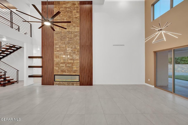 820 W Gate, El Paso, TX 79932 - unfurnished living room with a towering ceiling, stairs, a large fireplace, a ceiling fan, and tile patterned floors