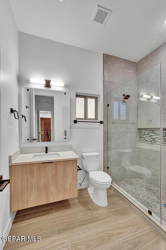 820 W Gate, El Paso, TX 79932 - bathroom with toilet, vanity, tiled shower, wood finished floors, and baseboards