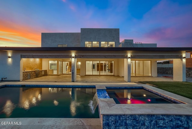 820 W Gate, El Paso, TX 79932 - back of property at dusk featuring a patio area, an outdoor pool, an in-ground hot tub, and stucco siding