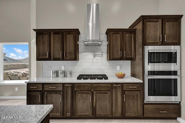 13404 Coldham St, El Paso, TX 79928 - kitchen featuring wall chimney exhaust hood, appliances with stainless steel finishes, dark brown cabinetry, and tasteful backsplash