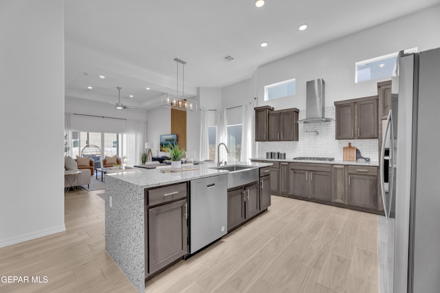 13404 Coldham St, El Paso, TX 79928 - kitchen with wall chimney exhaust hood, stainless steel appliances, a sink, decorative backsplash, and light wood-style floors
