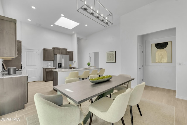13404 Coldham St, El Paso, TX 79928 - dining room featuring a skylight, light wood-style floors, recessed lighting, a towering ceiling, and baseboards