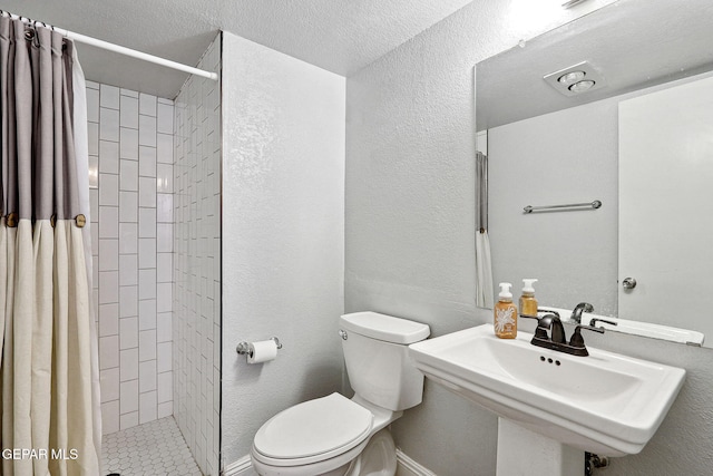 6008 Camino Alegre Dr, El Paso, TX 79912 - bathroom with toilet, a tile shower, a sink, and a textured wall