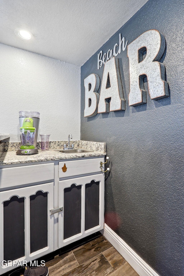 6008 Camino Alegre Dr, El Paso, TX 79912 - bathroom with a sink, wood finished floors, a textured ceiling, and baseboards