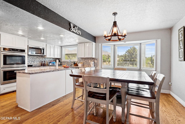 6008 Camino Alegre Dr, El Paso, TX 79912 - dining room with a textured ceiling, light wood finished floors, a chandelier, recessed lighting, and baseboards