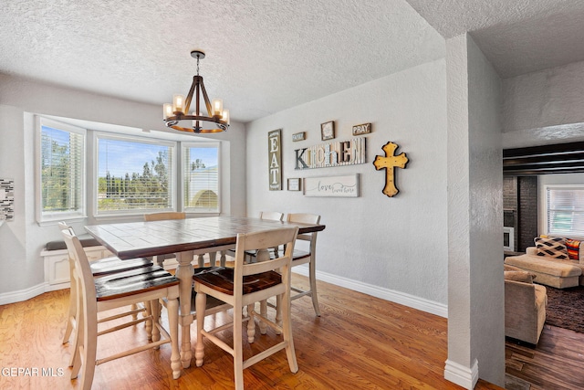 6008 Camino Alegre Dr, El Paso, TX 79912 - dining room featuring a textured ceiling, wood finished floors, baseboards, a textured wall, and a chandelier