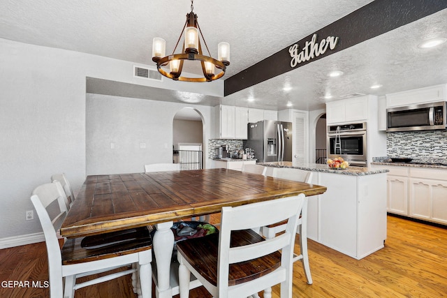 6008 Camino Alegre Dr, El Paso, TX 79912 - dining area with arched walkways, a chandelier, a textured ceiling, light wood-type flooring, and recessed lighting