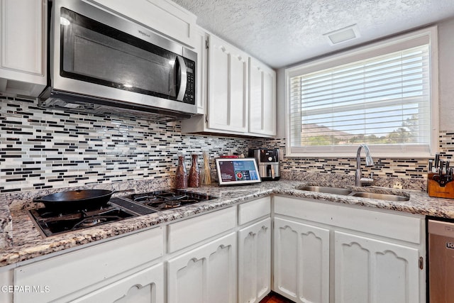 6008 Camino Alegre Dr, El Paso, TX 79912 - kitchen featuring stainless steel appliances, a sink, decorative backsplash, white cabinetry, and a textured ceiling