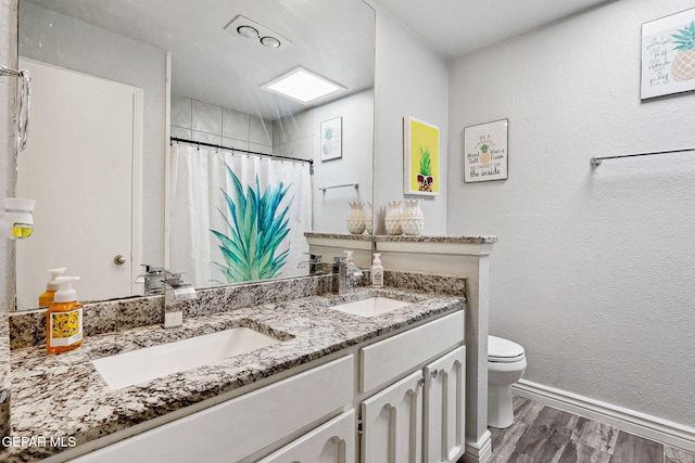 6008 Camino Alegre Dr, El Paso, TX 79912 - full bathroom with wood finished floors, toilet, double vanity, a shower with shower curtain, and baseboards