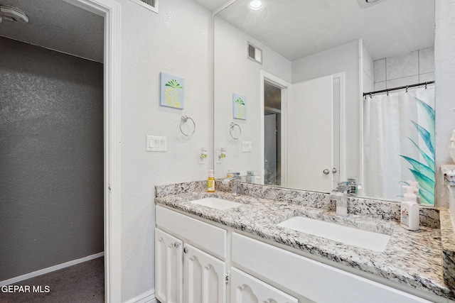 6008 Camino Alegre Dr, El Paso, TX 79912 - full bathroom featuring double vanity, a textured wall, curtained shower, and baseboards