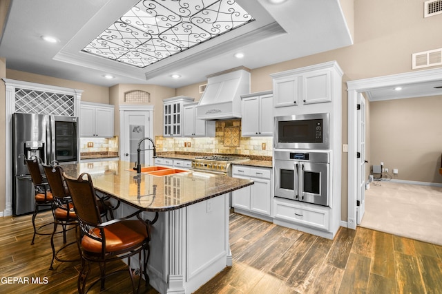 14624 Long Shadow Ave, El Paso, TX 79938 - kitchen with stainless steel appliances, a tray ceiling, custom range hood, a sink, and a kitchen bar
