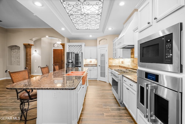 14624 Long Shadow Ave, El Paso, TX 79938 - kitchen featuring stainless steel appliances, a raised ceiling, arched walkways, a breakfast bar area, and ornamental molding