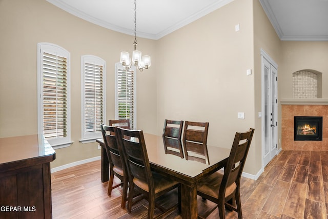14624 Long Shadow Ave, El Paso, TX 79938 - dining space with wood finished floors, ornamental molding, a chandelier, baseboards, and a tile fireplace